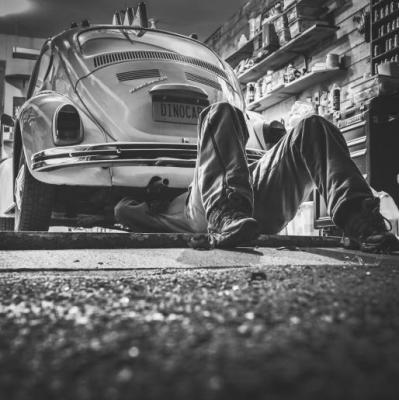 A mechanic working underneath an old car.