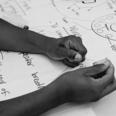 A close up of a pair of hands working on a large piece of paper.