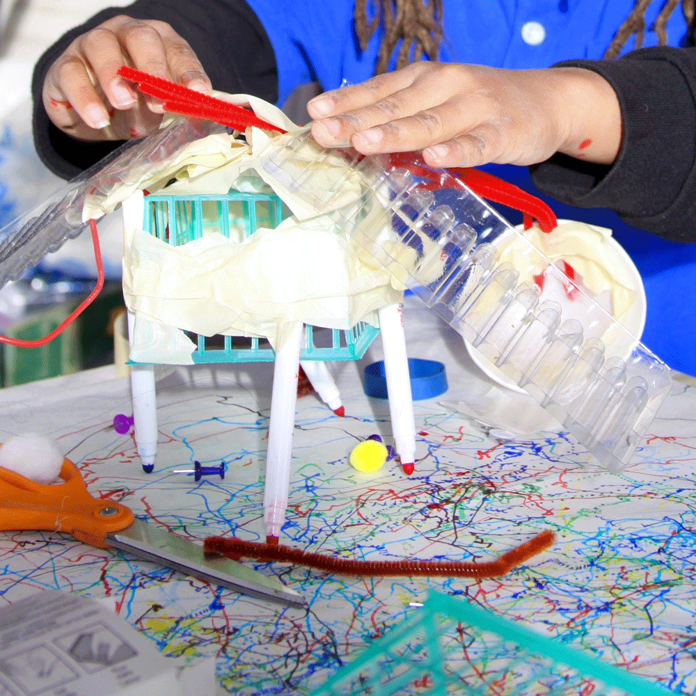 A young child making something from various objects.