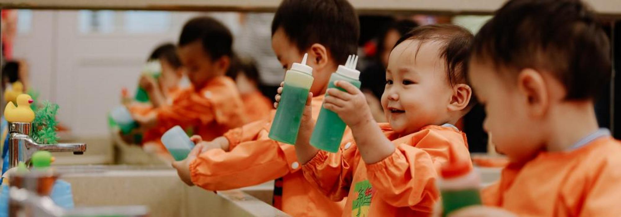 Young students playing with liquids in a large sink.