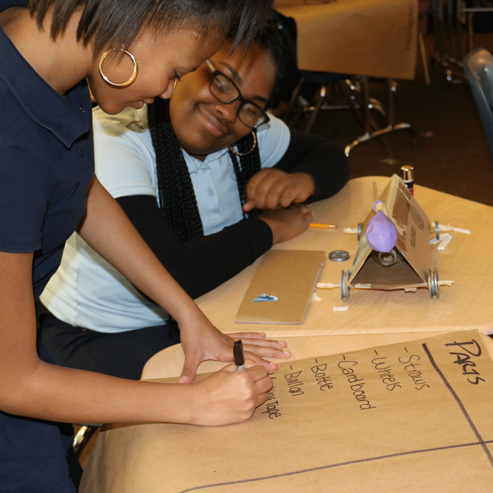 Two students writing a list on construction paper.