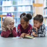 Three children read in a library together