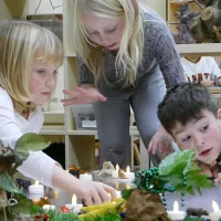 Three children play with plants in a classroom