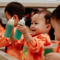 A toddler holds to paint bottles
