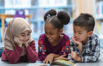 Three children read in a library together